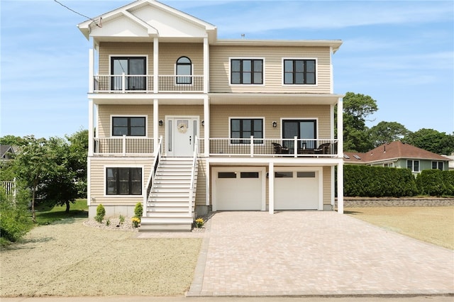 51 Burnett Rd, Warwick, RI 02889 - coastal home featuring a balcony, decorative driveway, stairway, an attached garage, and a porch