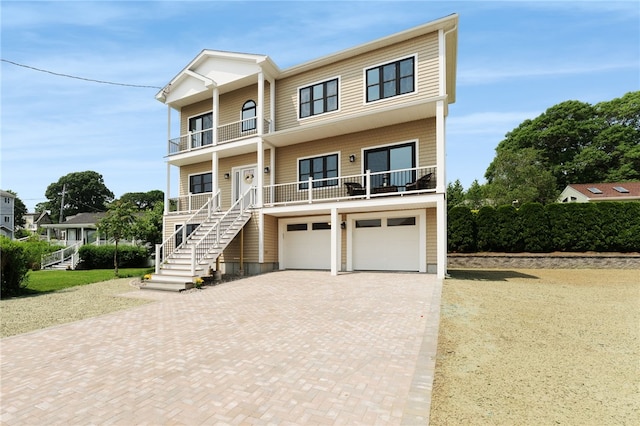 51 Burnett Rd, Warwick, RI 02889 - raised beach house with decorative driveway, a balcony, an attached garage, stairway, and covered porch