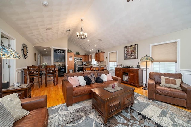 1421 Douglas Ave Unit E, North Providence, RI 02904 - living room featuring a chandelier, a wainscoted wall, light wood-style floors, plenty of natural light, and vaulted ceiling