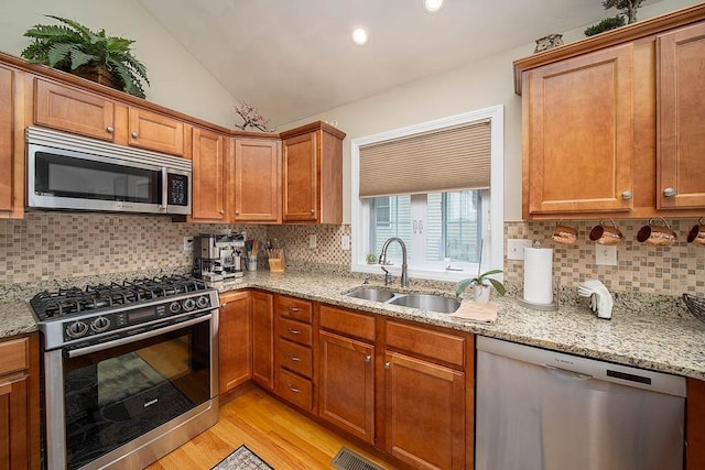 1421 Douglas Ave Unit E, North Providence, RI 02904 - kitchen featuring stainless steel appliances, a sink, light wood-style floors, brown cabinetry, and decorative backsplash
