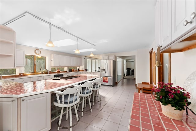 336 Switch Rd, Richmond, RI 02832 - kitchen with stainless steel fridge, tile counters, open shelves, a kitchen breakfast bar, and white cabinets