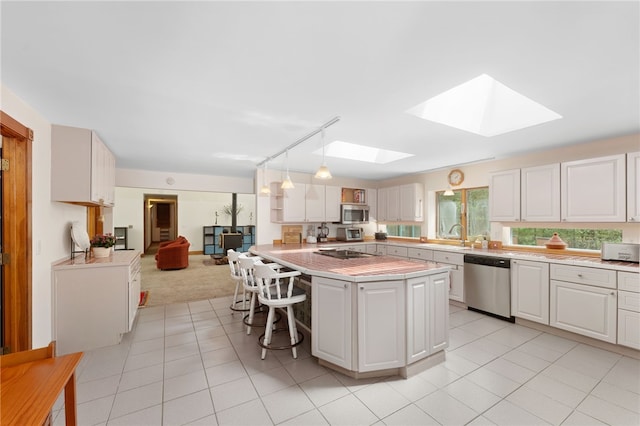336 Switch Rd, Richmond, RI 02832 - kitchen with appliances with stainless steel finishes, a skylight, light countertops, light tile patterned floors, and a breakfast bar area