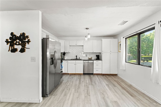 694 Orleans Ct, Warwick, RI 02886 - kitchen with stainless steel appliances, light wood finished floors, dark countertops, tasteful backsplash, and white cabinetry