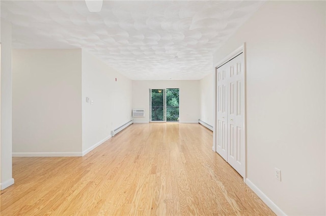 752 Quaker Ln Unit C311, Warwick, RI 02818 - empty room with a baseboard heating unit, light wood-type flooring, a wall mounted AC, and baseboard heating