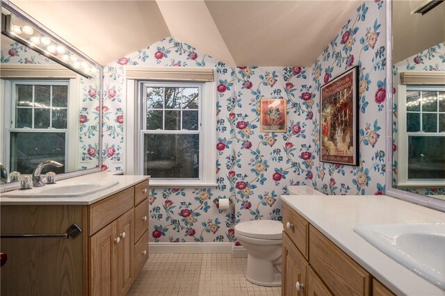 2 Cherry Ln, Bristol, RI 02809 - bathroom with wallpapered walls, baseboards, two vanities, vaulted ceiling, and tile patterned floors