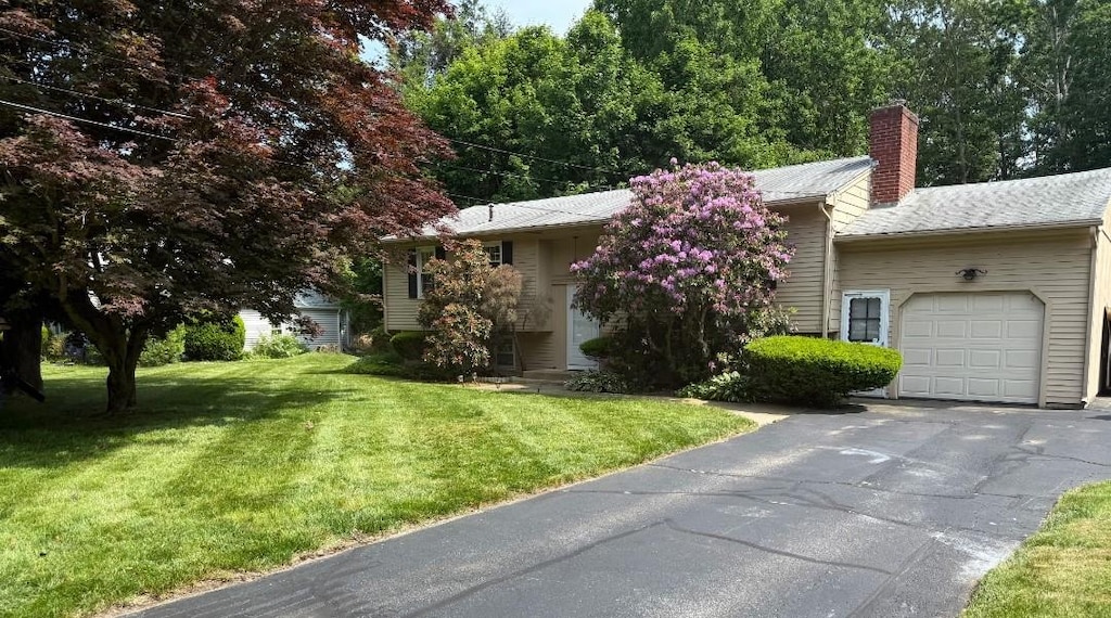 20 Maplewood Dr, Coventry, RI 02816 - view of front of house with an attached garage, a chimney, a front yard, and asphalt driveway