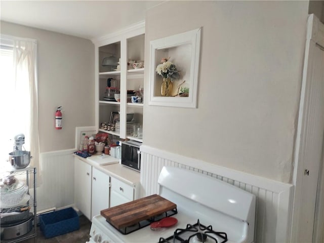 5 Peter St, Providence, RI 02904 - kitchen featuring a wainscoted wall, white cabinetry, light countertops, and stove