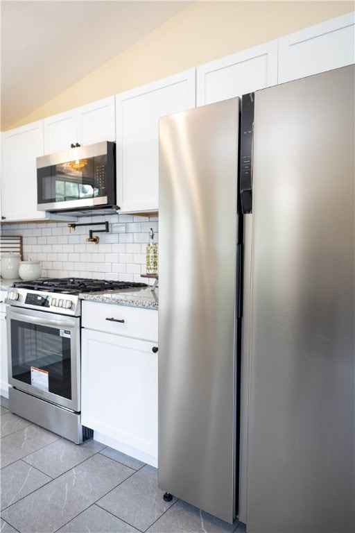 259 Buttonwoods Ave, Warwick, RI 02886 - kitchen featuring stainless steel appliances, decorative backsplash, white cabinetry, vaulted ceiling, and light stone countertops