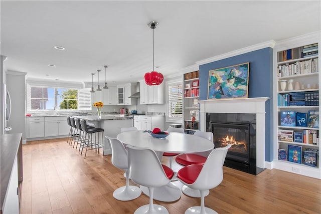 40 Kettle Point Ave, East Providence, RI 02914 - dining room with a fireplace with flush hearth, light wood-style floors, crown molding, recessed lighting, and built in shelves