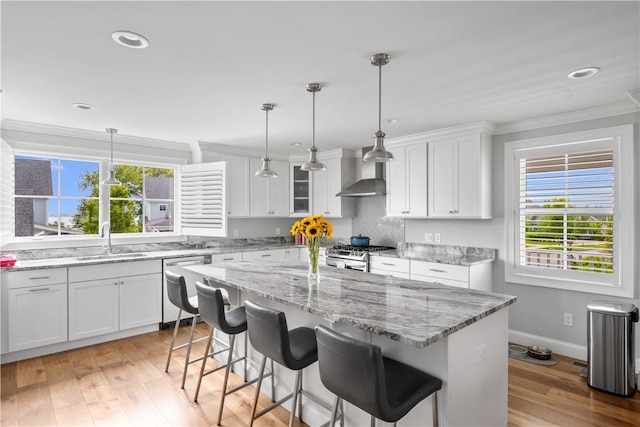 40 Kettle Point Ave, East Providence, RI 02914 - kitchen featuring dishwashing machine, wall chimney exhaust hood, stainless steel gas range oven, white cabinets, and a center island