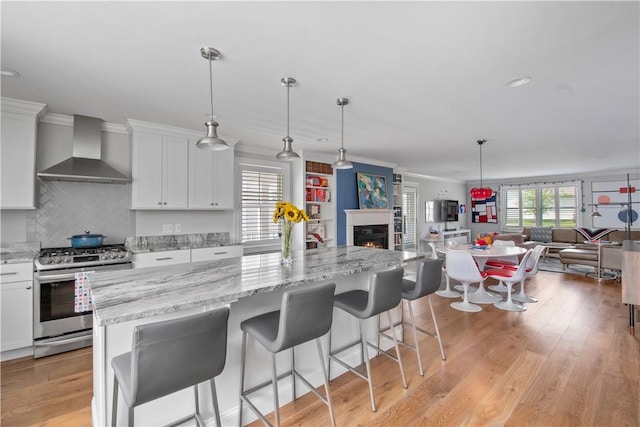 40 Kettle Point Ave, East Providence, RI 02914 - kitchen with wall chimney exhaust hood, gas range, open floor plan, a kitchen island, and light wood-style floors