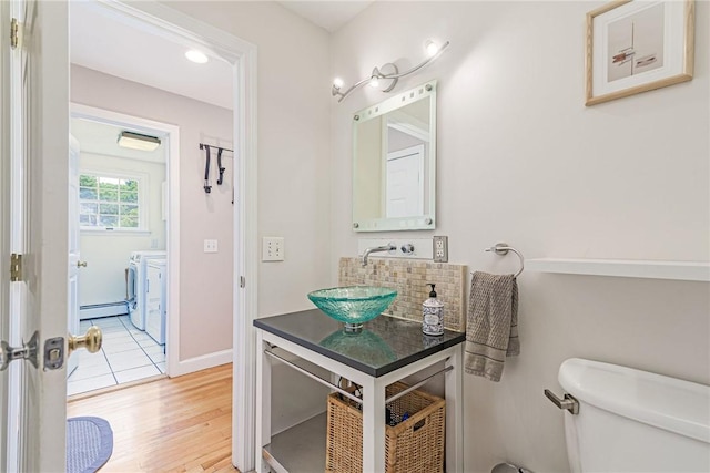 59 Intrepid Ln, Jamestown, RI 02835 - bathroom with washer and clothes dryer, toilet, vanity, a baseboard heating unit, and wood finished floors