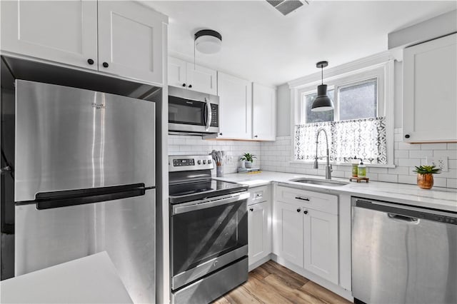 694 Windwood Dr Unit C, Tiverton, RI 02878 - kitchen featuring stainless steel appliances, a sink, white cabinets, light wood-style flooring, and decorative backsplash