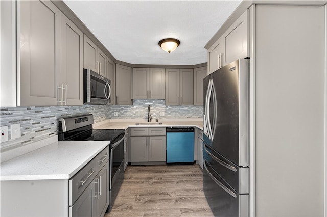 403 Pinewood Dr, Smithfield, RI 02917 - kitchen with stainless steel appliances, a sink, gray cabinetry, light wood-style floors, and decorative backsplash