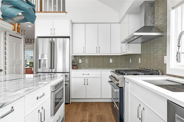 413 Atlantic Ave, Westerly, RI 02891 - kitchen featuring wall chimney range hood, appliances with stainless steel finishes, backsplash, wood finished floors, and white cabinets