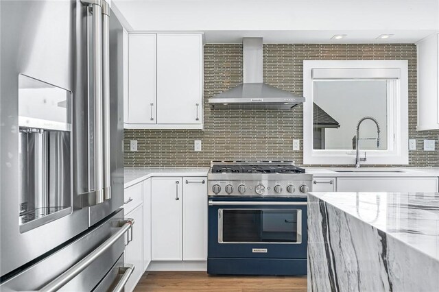 413 Atlantic Ave, Westerly, RI 02891 - kitchen featuring appliances with stainless steel finishes, wall chimney range hood, a sink, light stone countertops, and tasteful backsplash
