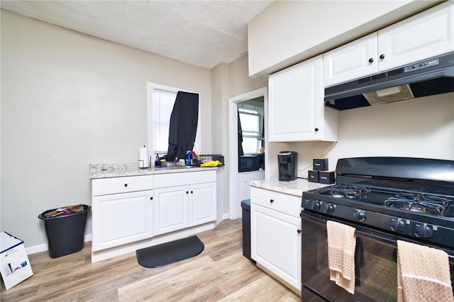 62 School St, Fall River, MA 02720 - kitchen featuring black range with gas cooktop, under cabinet range hood, light wood-style floors, white cabinetry, and light stone countertops