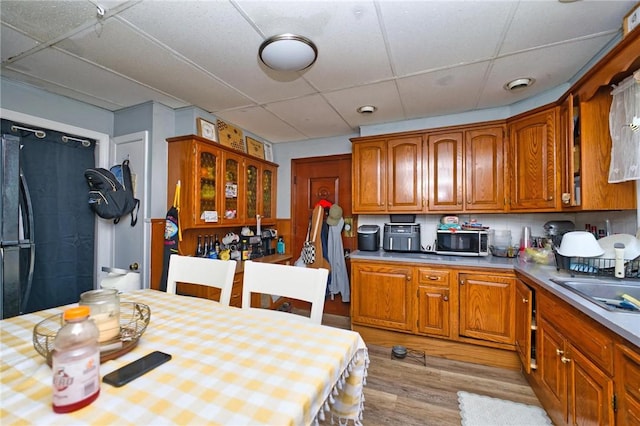 62 School St, Fall River, MA 02720 - kitchen featuring stainless steel microwave, light wood-style flooring, a paneled ceiling, glass insert cabinets, and light countertops