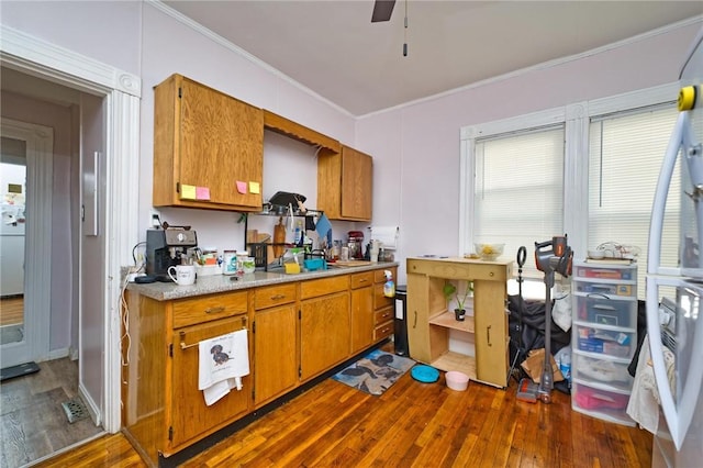 62 School St, Fall River, MA 02720 - kitchen with dark wood finished floors, crown molding, brown cabinets, light countertops, and freestanding refrigerator