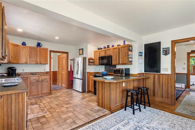 201 Paradise Ave, Middletown, RI 02842 - kitchen featuring black appliances, a peninsula, a sink, wainscoting, and a breakfast bar