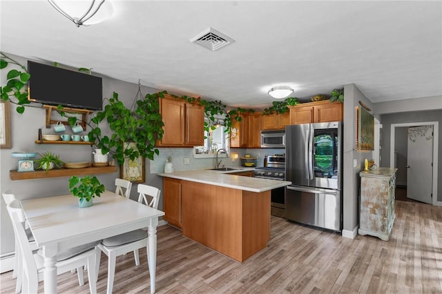 68 Everglade Ave, Warwick, RI 02886 - kitchen featuring appliances with stainless steel finishes, a peninsula, brown cabinetry, and light wood-style flooring