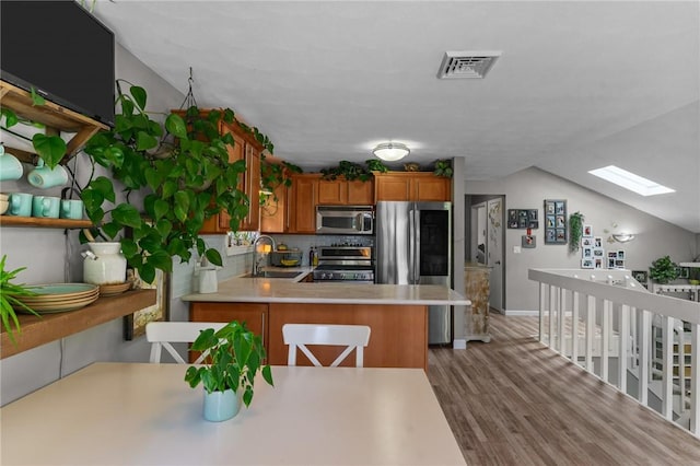 68 Everglade Ave, Warwick, RI 02886 - kitchen with appliances with stainless steel finishes, a skylight, brown cabinets, wood finished floors, and light countertops