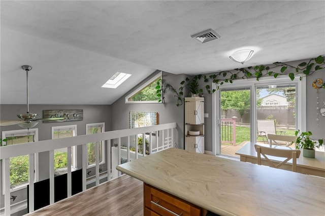 68 Everglade Ave, Warwick, RI 02886 - kitchen featuring a skylight, vaulted ceiling, brown cabinets, a ceiling fan, and wood finished floors