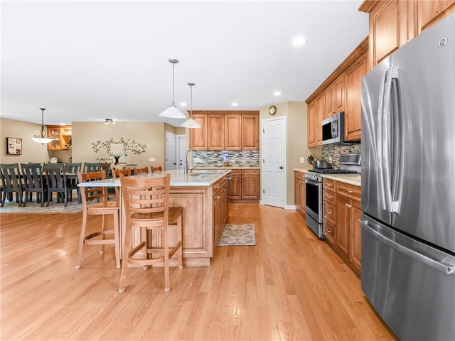 162 Pine Orchard Rd, Glocester, RI 02814 - kitchen with appliances with stainless steel finishes, light wood-type flooring, brown cabinets, decorative backsplash, and an island with sink