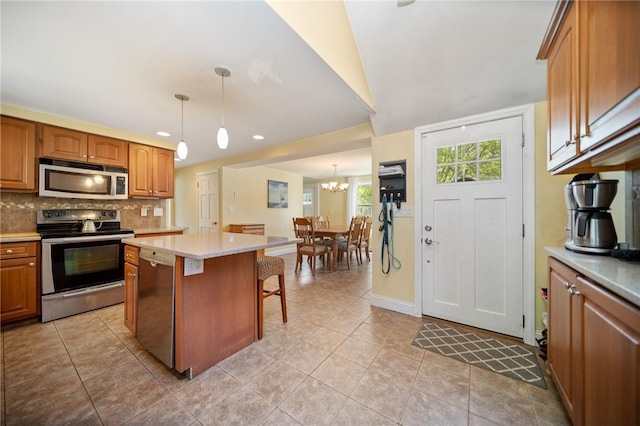 79 Pilgrim Dr, Warwick, RI 02888 - kitchen with stainless steel appliances, tasteful backsplash, light countertops, a chandelier, and brown cabinets