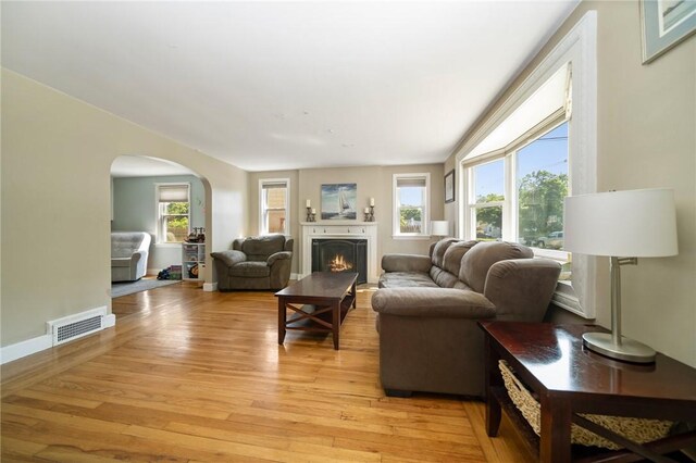 79 Pilgrim Dr, Warwick, RI 02888 - living area featuring arched walkways, light wood-style floors, a lit fireplace, and baseboards