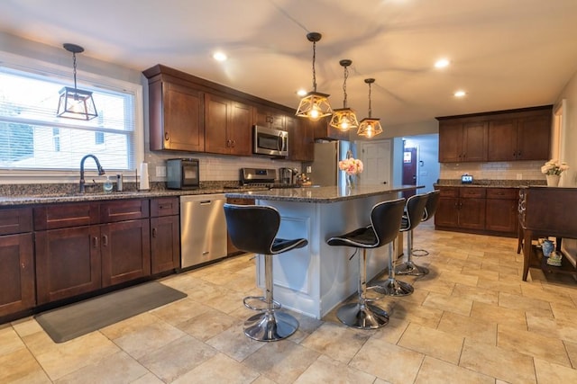 21 Baldwin Rd, Warwick, RI 02886 - kitchen featuring stainless steel appliances, backsplash, dark stone countertops, a center island, and a sink