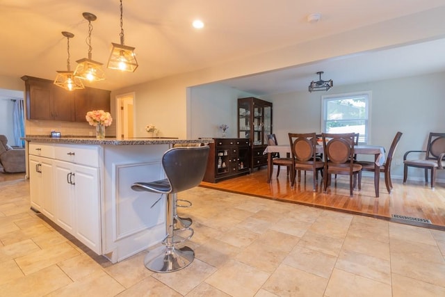 21 Baldwin Rd, Warwick, RI 02886 - kitchen with stone counters, decorative light fixtures, white cabinetry, a kitchen island, and backsplash