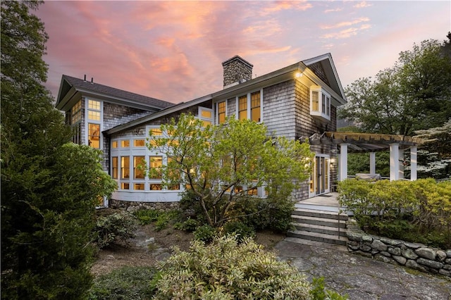 137 Cove Pt E, Charlestown, RI 02813 - property exterior at dusk with a pergola, a chimney, and a sunroom