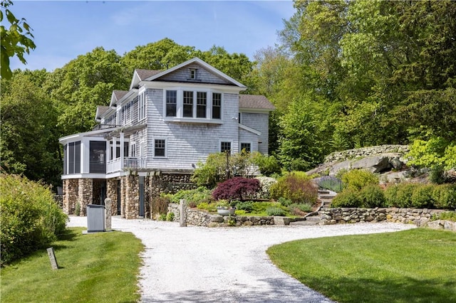 137 Cove Pt E, Charlestown, RI 02813 - view of front of house with driveway, a front lawn, stone siding, and a sunroom