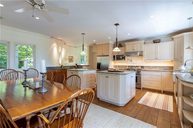 137 Cove Pt E, Charlestown, RI 02813 - kitchen with stainless steel appliances, under cabinet range hood, a center island, crown molding, and light wood-type flooring