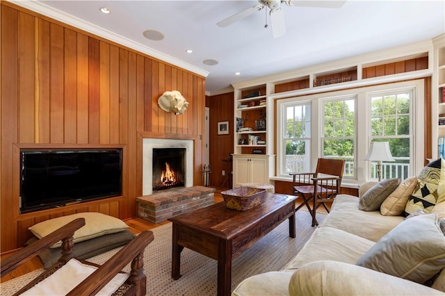 137 Cove Pt E, Charlestown, RI 02813 - living room with healthy amount of natural light, wooden walls, wood finished floors, a brick fireplace, and a ceiling fan
