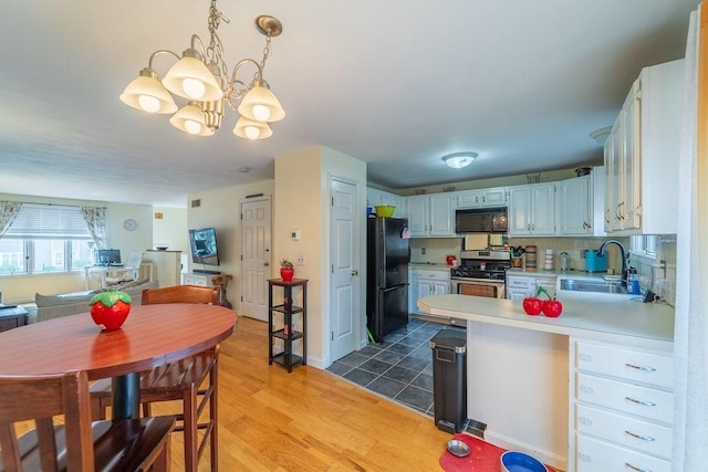 7 Tamarac Dr Unit F, Smithfield, RI 02828 - kitchen with black appliances, a peninsula, light countertops, a chandelier, and light wood finished floors