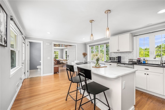 64 Dean St, Cranston, RI 02920 - kitchen with crown molding, light wood finished floors, white cabinetry, a center island, and appliances with stainless steel finishes