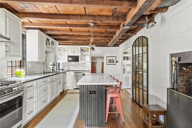 35 Second St, Newport, RI 02840 - kitchen with appliances with stainless steel finishes, dark wood finished floors, tasteful backsplash, white cabinetry, and a wooden ceiling with exposed beams