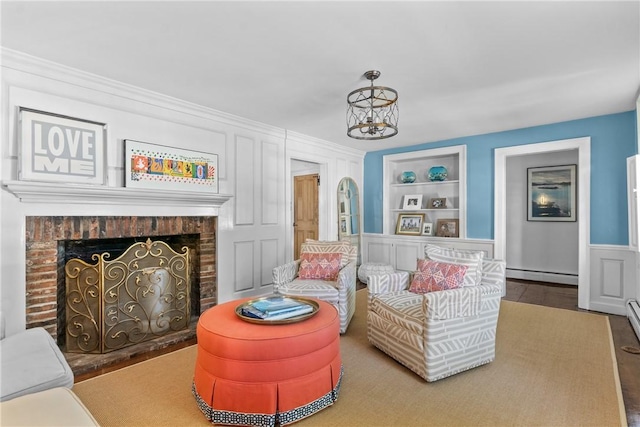 35 Second St, Newport, RI 02840 - living room with a baseboard radiator, built in shelves, a brick fireplace, a chandelier, and wainscoting
