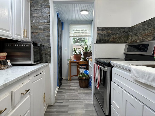 25 Eddy St, West Warwick, RI 02893 - kitchen featuring stainless steel range with electric stovetop, light wood finished floors, white cabinets, and light stone counters