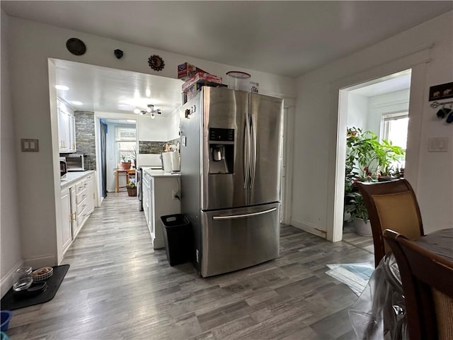 25 Eddy St, West Warwick, RI 02893 - kitchen with stainless steel fridge with ice dispenser, plenty of natural light, white cabinets, and light countertops