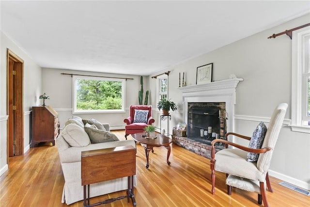 373 Fletcher Rd, North Kingstown, RI 02852 - living area featuring a brick fireplace, light wood finished floors, and a baseboard radiator