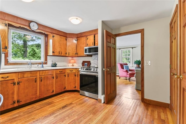 373 Fletcher Rd, North Kingstown, RI 02852 - kitchen featuring appliances with stainless steel finishes, light countertops, decorative backsplash, light wood-type flooring, and brown cabinets