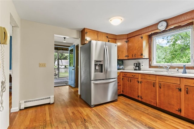 373 Fletcher Rd, North Kingstown, RI 02852 - kitchen featuring stainless steel fridge with ice dispenser, baseboard heating, light countertops, light wood-style floors, and brown cabinets
