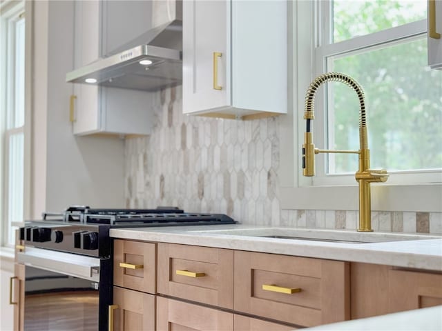 1314 Chalkstone Ave, Providence, RI 02908 - kitchen featuring wall chimney range hood, stainless steel range with gas cooktop, backsplash, and light stone counters