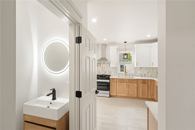 1314 Chalkstone Ave, Providence, RI 02908 - kitchen with gas range, wall chimney range hood, backsplash, light countertops, and decorative light fixtures