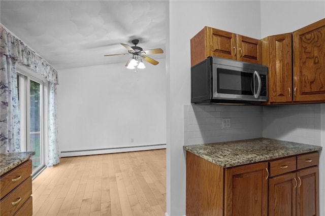2 Birch St, Johnston, RI 02919 - kitchen with stainless steel microwave, baseboard heating, decorative backsplash, and brown cabinetry