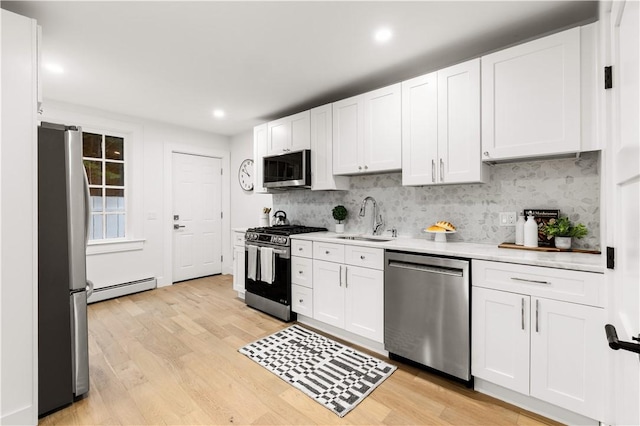51 Poplar St Unit 1L, Newport, RI 02840 - kitchen with appliances with stainless steel finishes, baseboard heating, light countertops, backsplash, and white cabinets