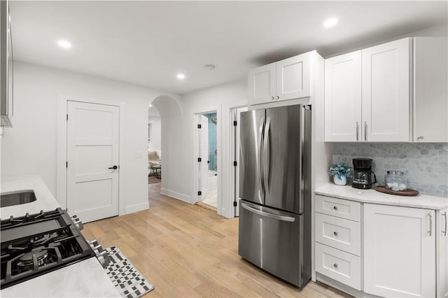 51 Poplar St Unit 1L, Newport, RI 02840 - kitchen with freestanding refrigerator, arched walkways, light countertops, white cabinets, and light wood-style floors